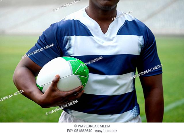African american male rugby player holding a rugby ball in stadium