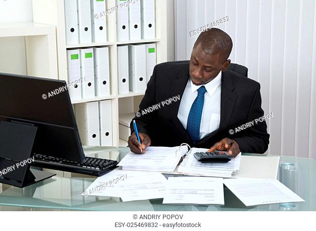 Young African Businessman Calculating Finance Bills In Office