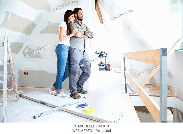 Couple in attic to be renovated looking out of window