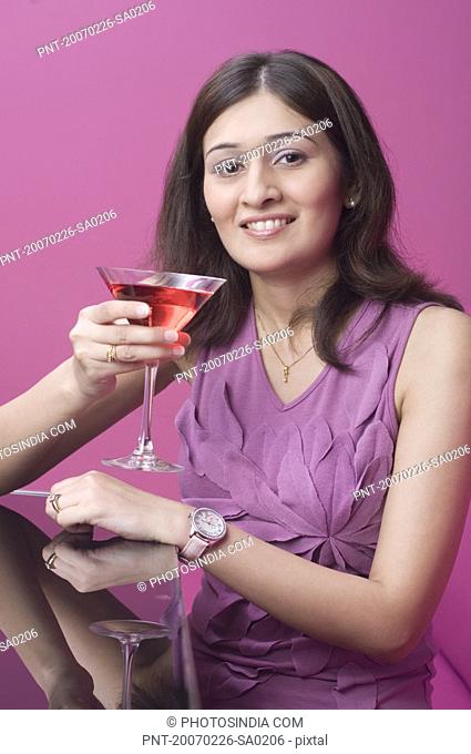 Portrait of a young woman holding a martini and smiling