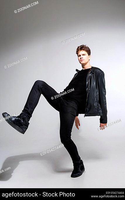full length portrait of young fit man in dark cloths on the white background. Young Male Fashion Model Posing In Casual Outfit