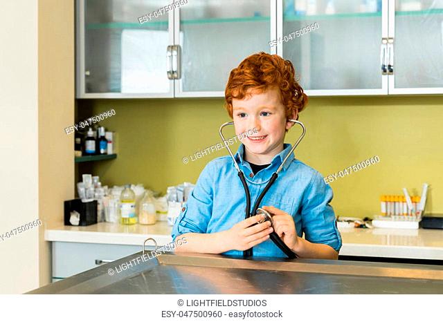 Cute red haired boy with stethoscope at clinic