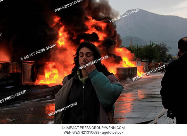 Firefighters try to locate a fire as people watch and take pictures of bon fire after a gas station explosion in the town of Vratca east of the Bulgarian...