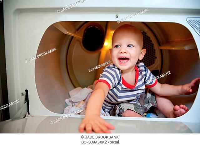 Baby boy sitting in tumble dryer