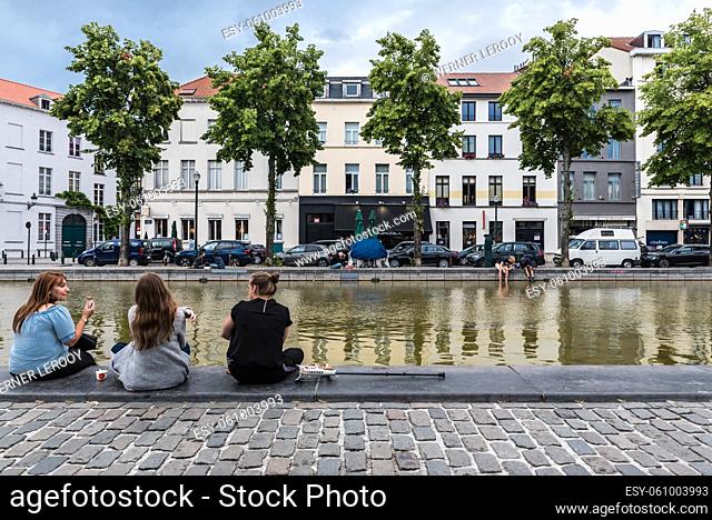 Brussels Old Town, Belgium - 07 18 2019 People sitting at the Anspach fountain at the Saint Catherine Square
