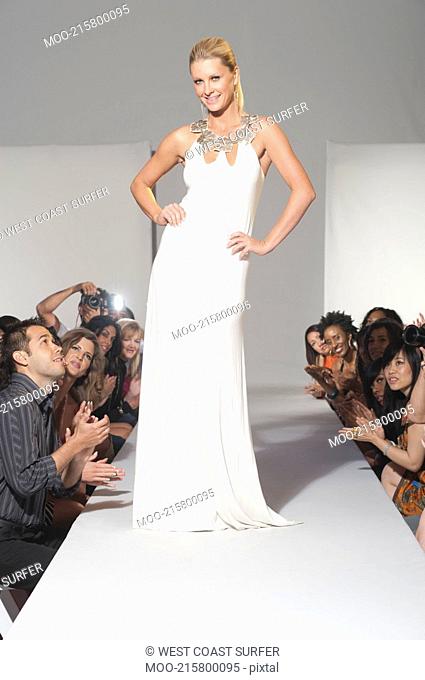 Woman stands in bridalwear on fashion catwalk