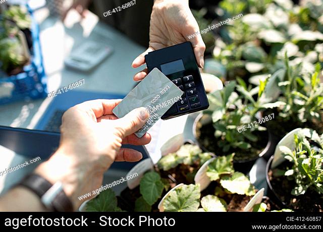 Close up customer paying for plants with smart card