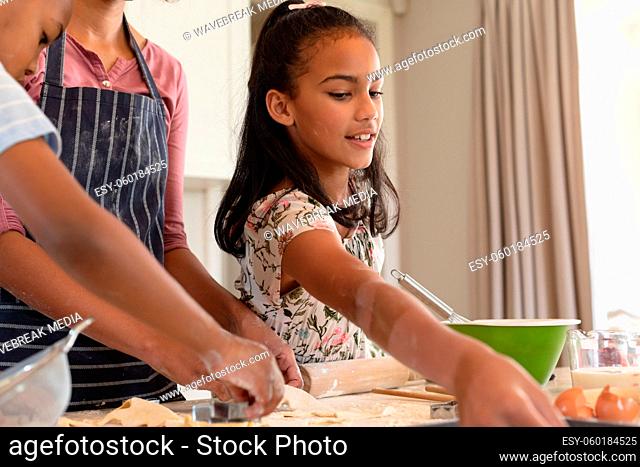 Happy african american mother with son and daughter baking in kitchen, cutting cookies
