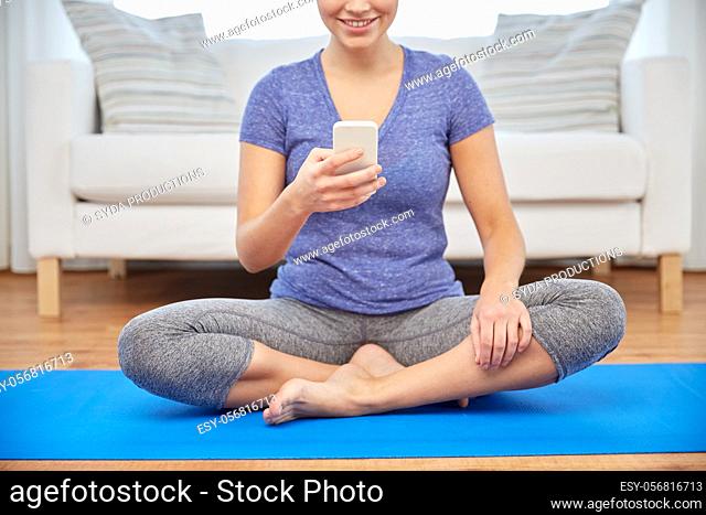 woman with smartphone sitting on mat at home