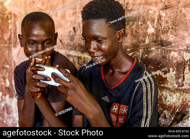 Apprentices using a cell phone in a garage in Fatick, Senegal, West Africa, Africa