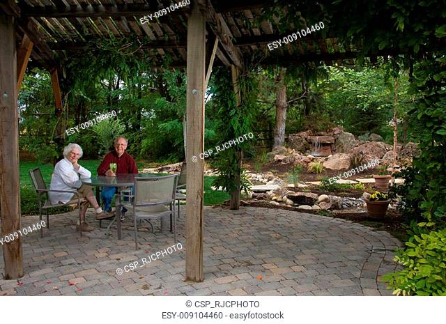 Elderly man and woman sitting in their yard