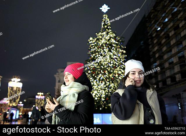 RUSSIA, MOSCOW - DECEMBER 21, 2023: Young women stroll past a Christmas tree. Mikhail Tereshchenko/TASS