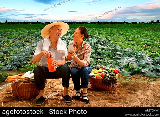 Peasant couple sat in the farm see a mobile phone