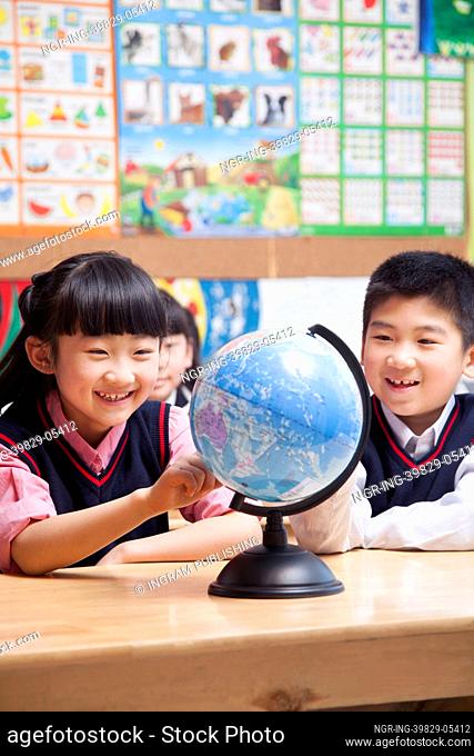 Schoolchildren looking at a globe in the classroom