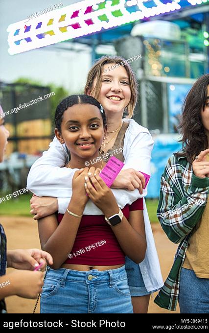 A happy, diverse group of girl friends hang out at the county fair on a summer night