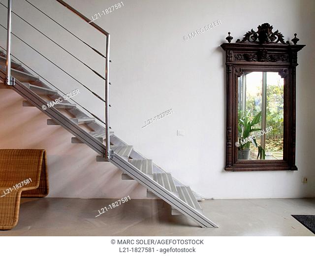 Big wooden mirror. Metallic staircase. Cane armchair. Interior designed by Gabriel Rodriguez