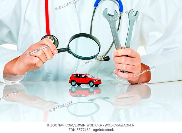 Ein Modell eines Autos wird von einem Arzt untersucht. Symbolfoto für Werkstatt, Service und Autokauf