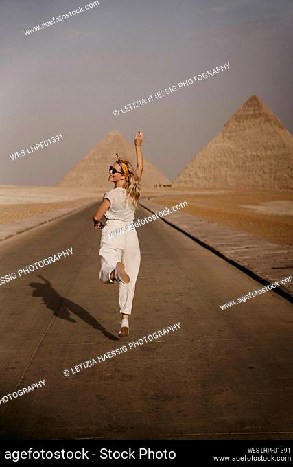 Female tourist running along road leading to Giza Pyramids