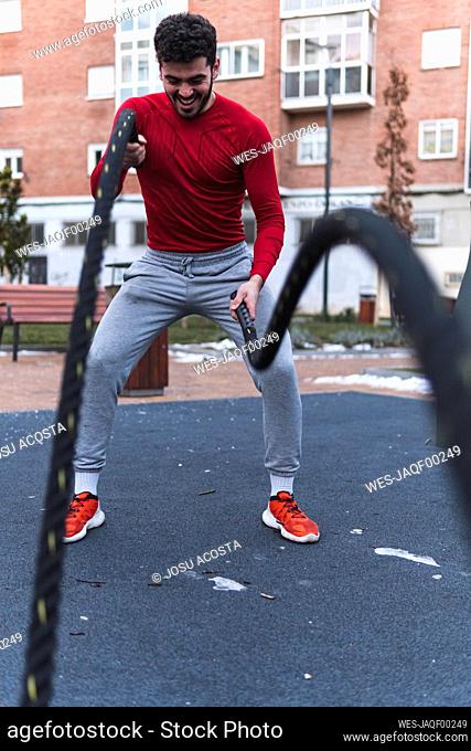 Young sportsperson exercising with rope while standing on training ground in city