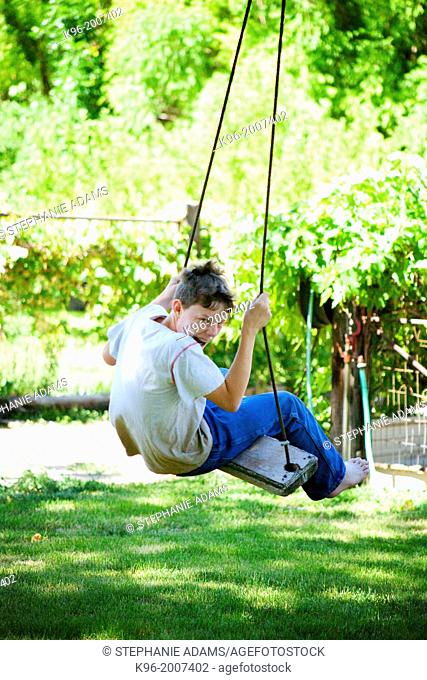 Young boy making faces while swinging