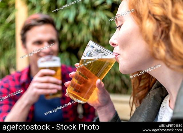 Woman drinking beer in glass at pub