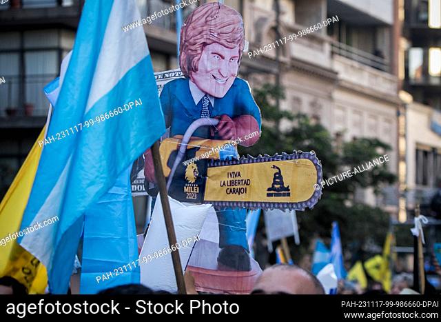 16 November 2023, Argentina, Cordoba: A cardboard doll depicts the right-wing conservative presidential candidate Milei with a chainsaw and the snake that his...