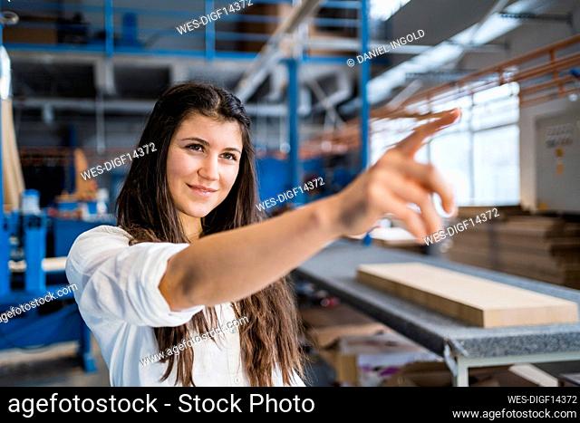 Smiling inspector pointing while standing at industry