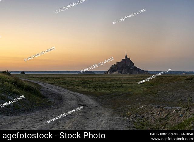 12 August 2021, France, Le Mont Saint Michel: Dusk at Mont Saint Michel. The rocky monastery island in the Normandy tidal flats is once again attracting...