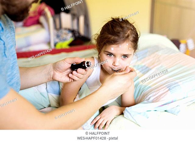 Girl having chickenpox receiving medicine in bed