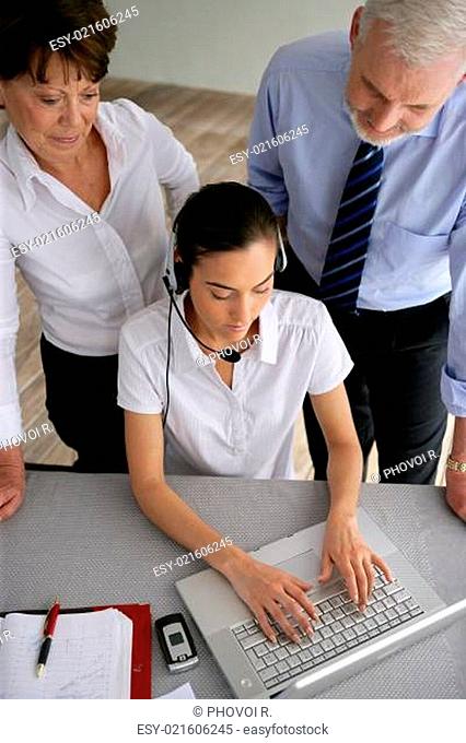 Business couple overseeing a woman talking through a headset