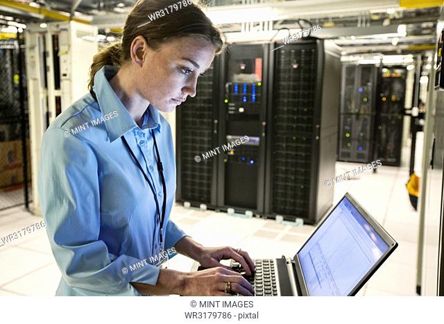 Caucasian woman technician running diagnostics on computer servers in a server farm