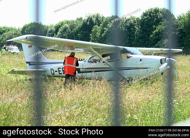17 June 2021, Hamburg: A Cessna stands in the grass behind a fence at Hamburg Airport. The small aircraft had run off the runway and come to rest in the grass