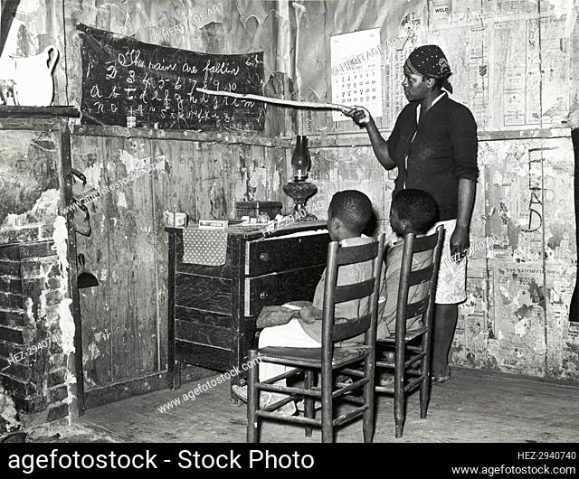 Negro mother teaching children numbers and alphabet in home of sharecropper.., Jan 1939. Creators: Farm Security Administration, Russell Lee