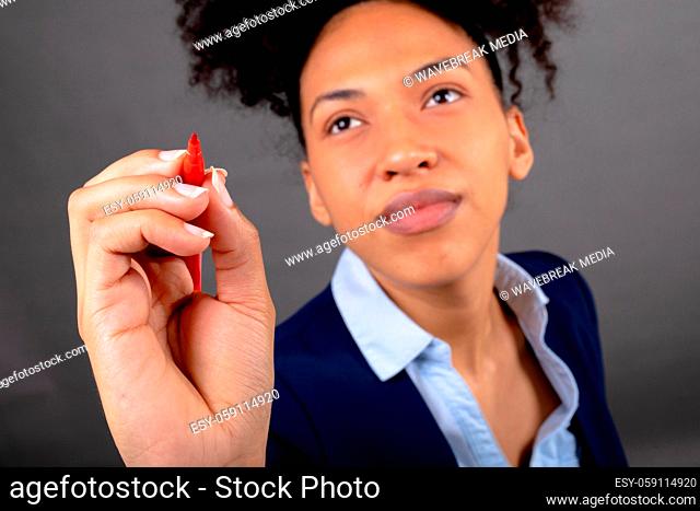 African american businesswoman writing on invisible screen with marker against grey background