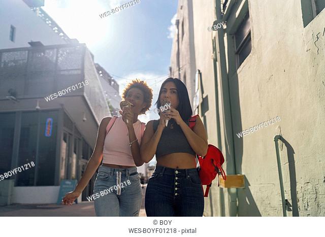 USA, Florida, Miami Beach, two female friends eating ice cream cones in the city