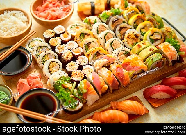 Above view of various sushi and rolls placed on wooden board. Japanese food fest. Top view, flat lay
