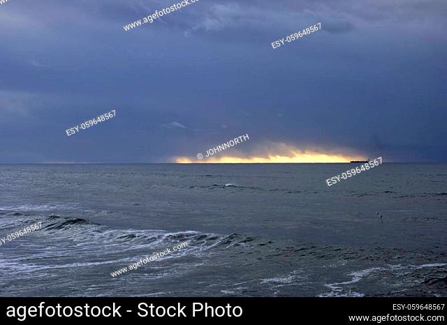 Dark blue sunset before rain and storm at sea seeing a ship on the horizon