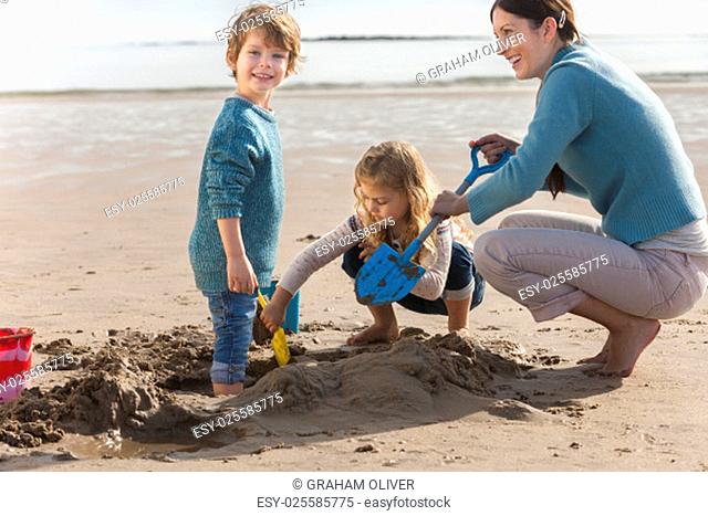 Mother playing on the beach with her son and daughter