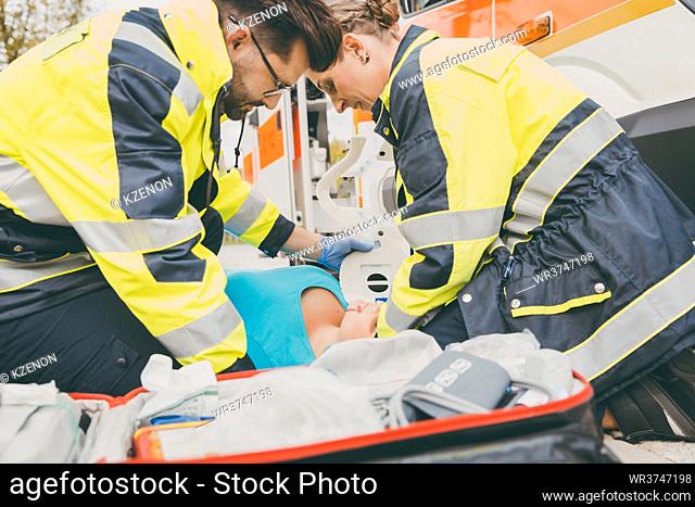 Paramedics performing first aid at ambulance, helping a woman