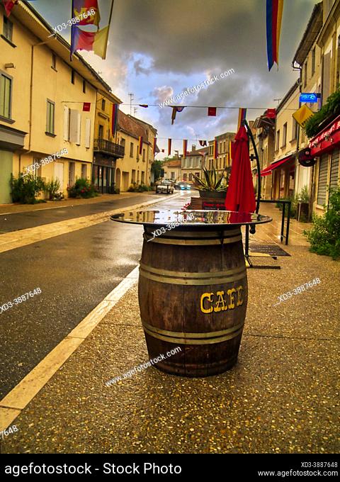 wooden barrel used as a cafe table on Rue Euigene Mazelie in the village of Lauzun on a stormy evening, Lot-et-Garonne Department, Nouvelle-Aquitaine, France