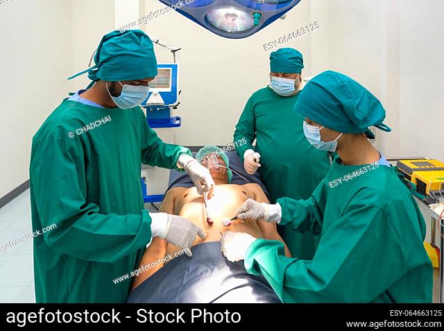 Group of surgeons and nurse in surgical green gown uniform performing surgical operation in operating room. Emergency surgical care concept