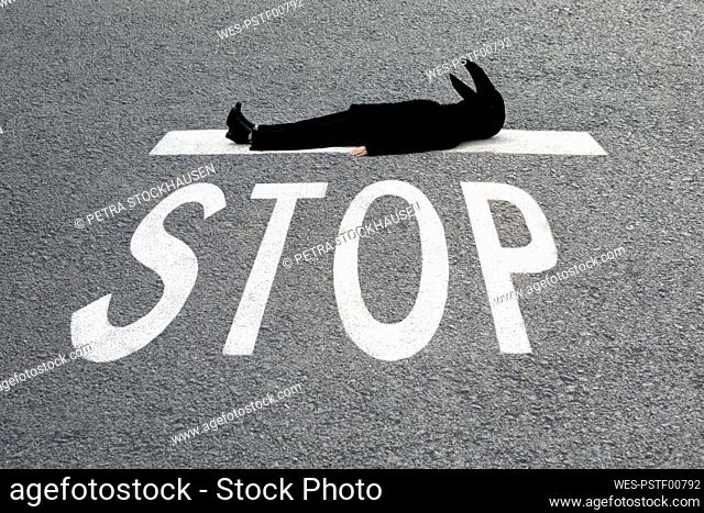 Female in crow costume lying down at STOP sign on road