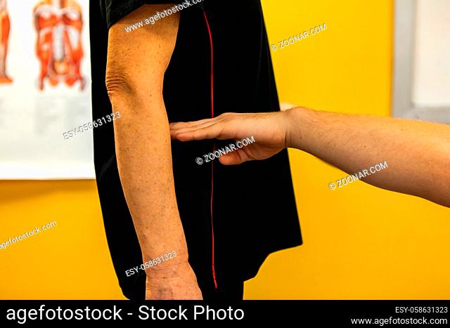 A close up and side profile view on the hands of a Swedish massage teacher demonstrating the human anatomy on a real life pupil, mid waist height