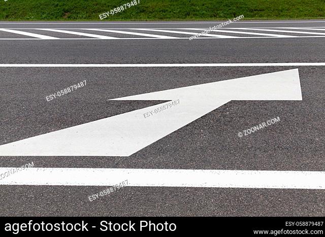 white big arrow on the asphalt road, indicating the direction of movement