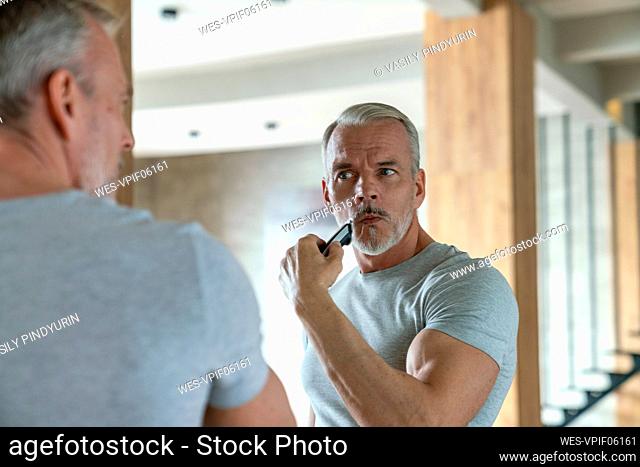 Man shaving with electric razor at home