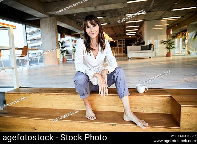 Smiling mature woman sitting on steps at home
