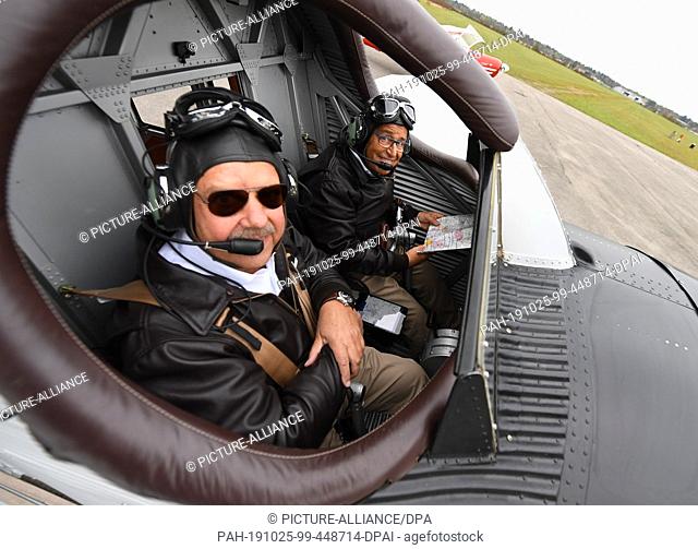 25 October 2019, Bavaria, Oberschleißheim: Owner Dieter Morszeck (l) and pilot Kurt Waldmeier sit in the open cockpit of a replica of the first all-metal...