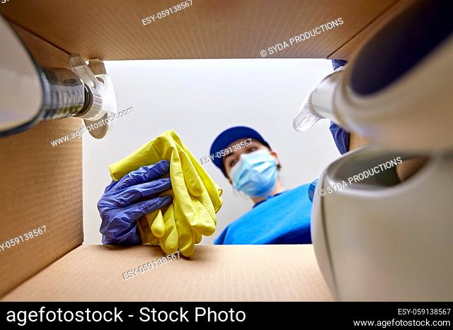 woman in mask packing cleaning supplies in box
