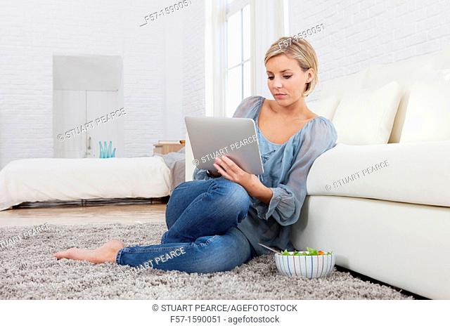 Young woman having lunch while socializing on her tablet computer