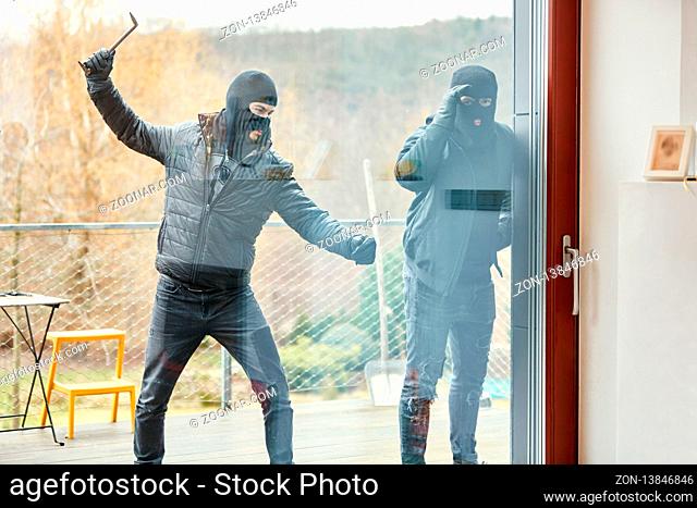 Einbrecher schlagen Scheibe einer Tür auf der Terrasse vom Haus ein beim Einbruch